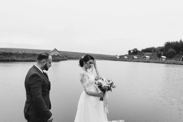 Os recém-casados caminham perto do lago no dia do casamento — Fotografia de Stock