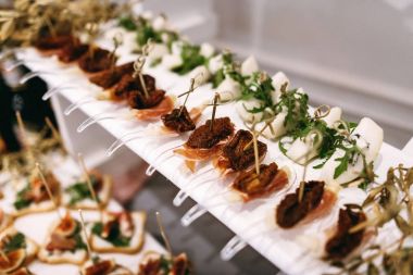 et ile kurutulmuş domates, roka açık büfe bir tablo ile bir armut. Düğün masa. Beyaz bir masada şaşırtıcı atıştırmalıklar sunulmaktadır