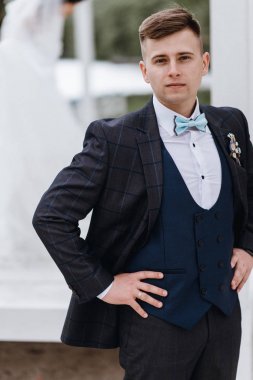 Yakışıklı genç damat takım elbise ve kravat açık havada 