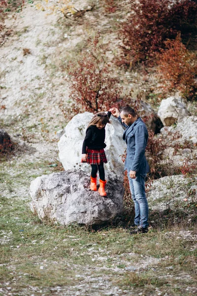 Girl standing on rock and man holding hand