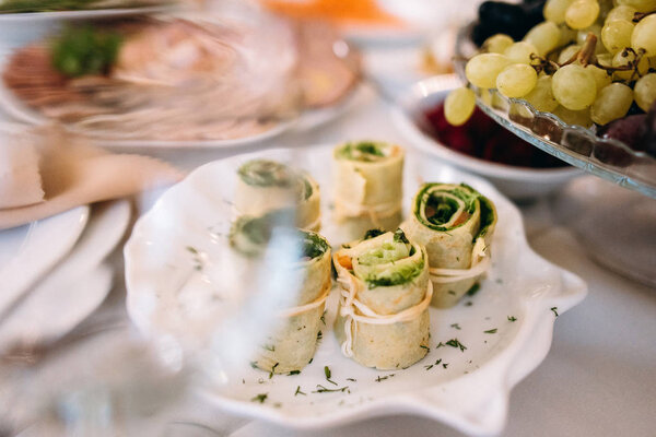 Close view of pancake rolls with salmon and spinach tied with Armenian braided string cheese served on white plate