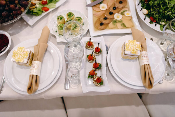 Festive wedding guest table setting with forks, knives, glasses and napkins