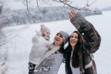 Küçük kızı elinde tutan ve having fun kış parkta birlikte anne
