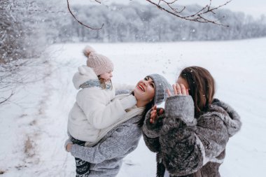 Küçük kızı elinde tutan ve having fun birlikte kış döneminde anne