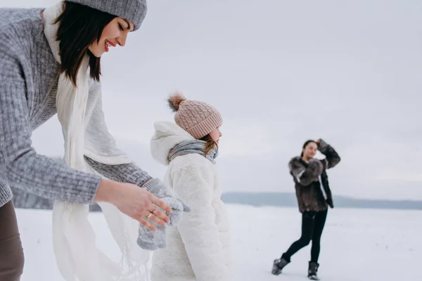 Mother taking gloves on and daughters enjoying winter time on background