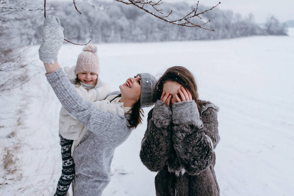 Mother holding smaller daughter in hands and having fun together in winter time