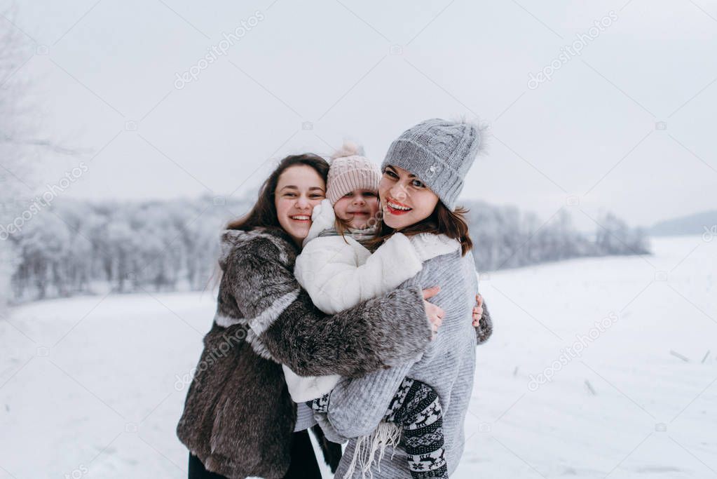 Mother cuddling with daughters in winter park