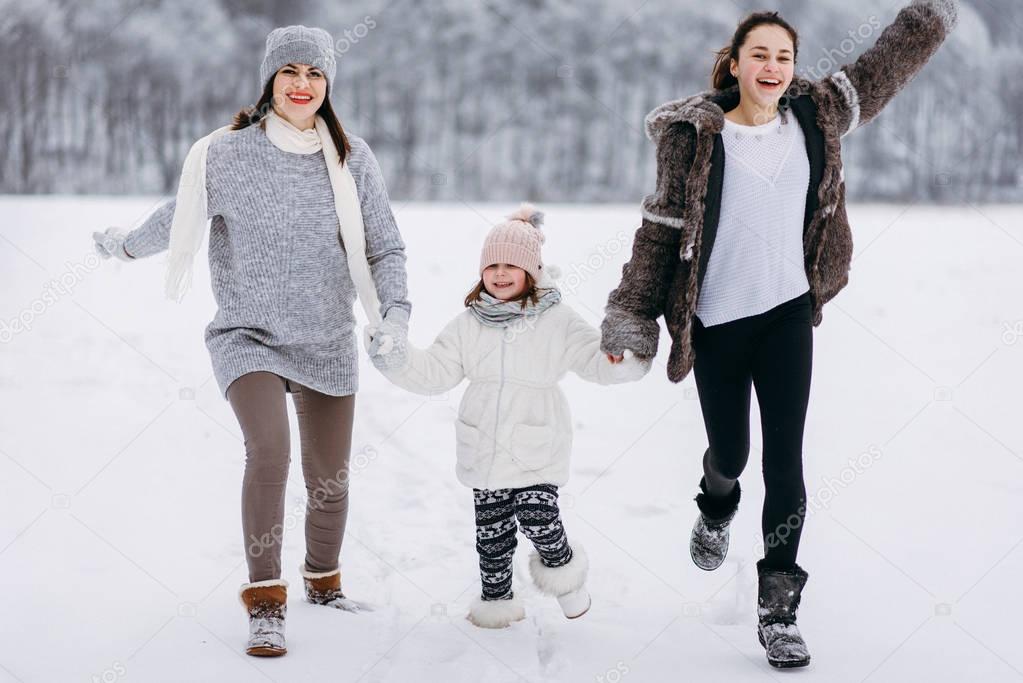 Front view of family running on snow on winter park background