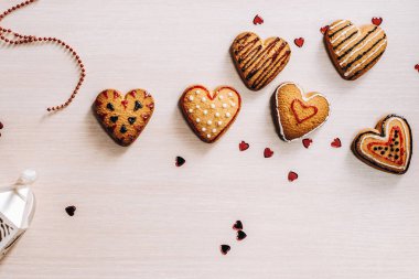 Kompozisyon ile dekore edilmiş kalp şeklinde kurabiye ve arka plan üzerinde kırmızı glitter Kalpler.