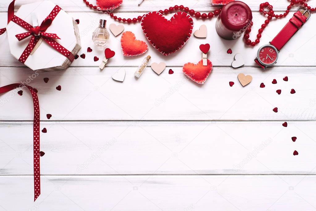 Valentines day background with red hearts, clothes pegs, box and perfume on wooden planks background