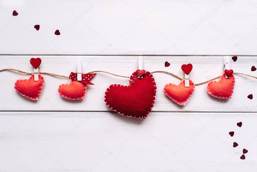 Composition of five red hearts attached with clothespins to a rope