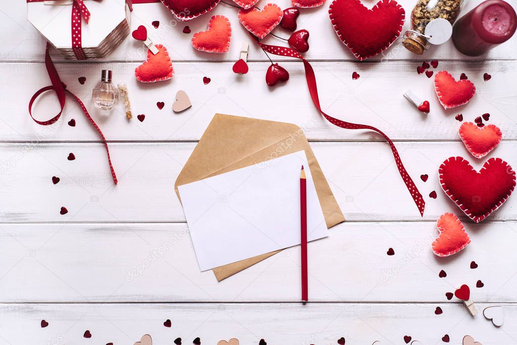 Composition with red hearts, pencil, paper and letter on wooden planks background