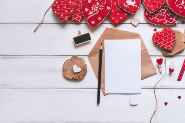 Sevgililer günü için el yapımı kırmızı sırlı Çerezler, mektup, kağıt parçası ve ahşap plakalar zemin üzerine kalem ile şenlikli kompozisyon.
