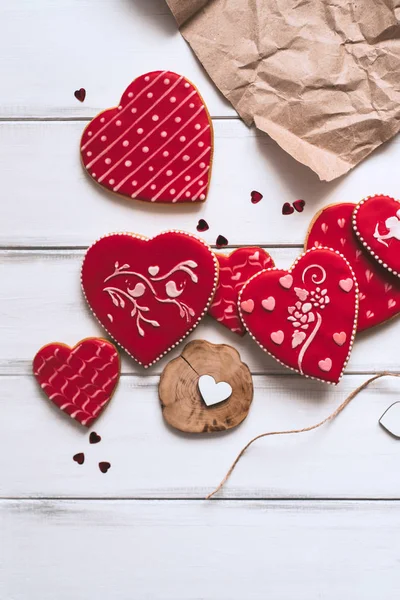 Festive composition with red glazed cookies, paper piece on wooden planks background for romantic day.