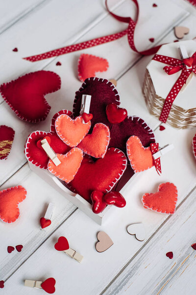 Декоративная композиция с сердцами и коробкой на фоне деревянных досок
.