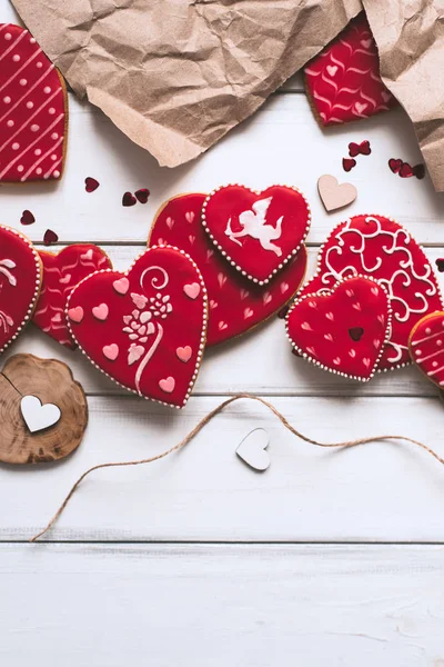Festive composition with red glazed cookies, paper piece on wooden planks background for romantic day.