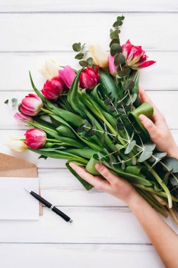Lale buketi el ve açılan zarf kağıt ve kalem arka planda tutan kadın