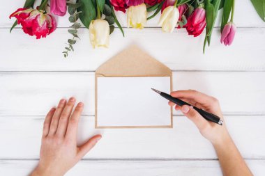 Beyaz kağıt ve Lale arka plan üzerinde yazma kadının Üstten Görünüm