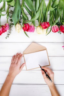 Beyaz kağıt ve Lale arka plan üzerinde yazma kadının Üstten Görünüm