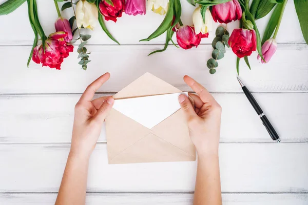 View of female hands opening envelope and tulips on background