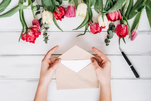 View of female hands opening envelope and tulips on background