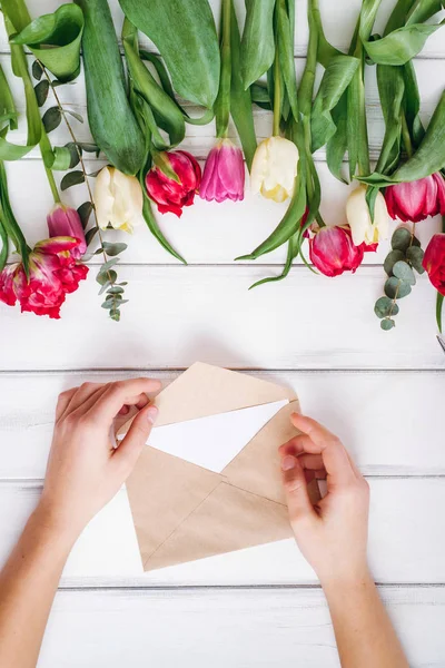 View of female hands opening envelope and tulips on background