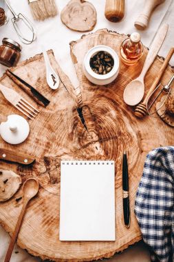 Defter, kalem ve farklı mutfak aksesuarları ile sawed ahşap arka plan üzerinde Üstten Görünüm