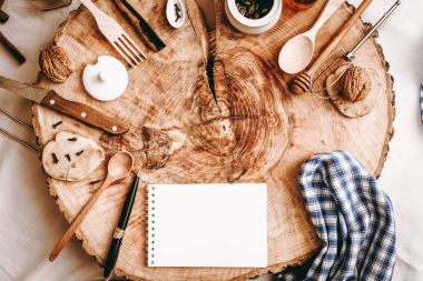 Defter, kalem ve mutfak aksesuarları ile sawed ahşap arka plan üzerinde Üstten Görünüm