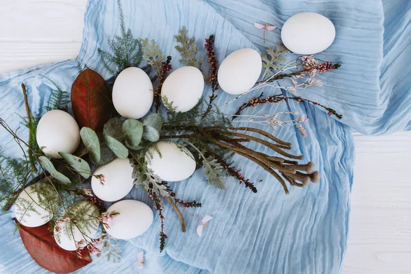 由鸡蛋 蓝色披肩 芽和茎组成的白色木板背景的花卉组合物 — 图库照片