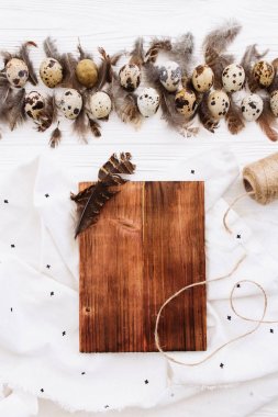 Bıldırcın yumurtası, tüyler, yönetim kurulu, iplik ve Tekstil Beyaz ahşap masa üstüne kenarlıklı dekoratif kompozisyon
