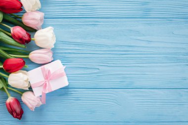Hediye kutusu ile mavi ahşap arka plan üzerinde sol tarafında satırda döşeme renkli Lale çiçek kompozisyon