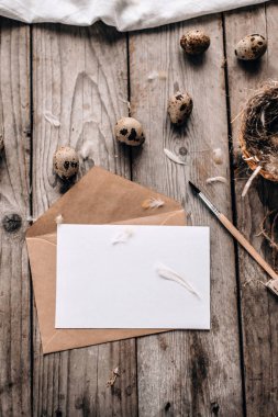 Bıldırcın yumurtası, fırça, ile şenlikli kompozisyon üstten görünüm zarf ile açık mektup ve dikey ahşap plakalar arka plan tüyler