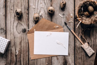 Bıldırcın yumurtası, fırça, ile şenlikli kompozisyon üstten görünüm zarf ile açık mektup ve dikey ahşap plakalar arka plan tüyler