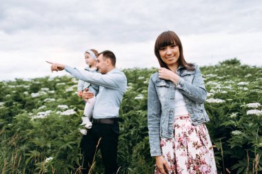 Kızı elinde tutan ve gülümseyen ve kameraya poz annesi ise bir şey üzerinde parmak ile işaret eden babası