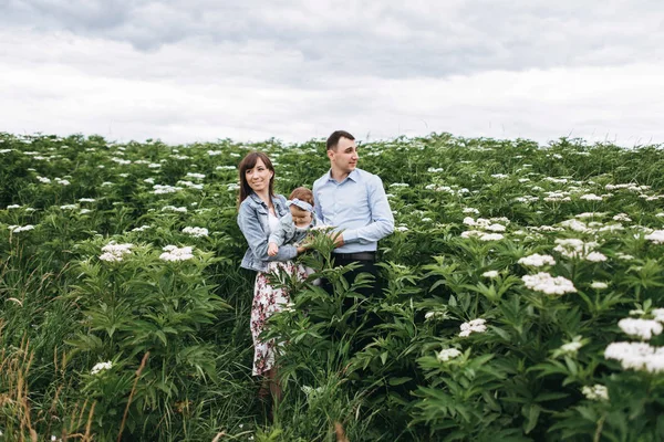 Glückliche Eltern Stehen Zusammen Und Umarmen Tochter Blühenden Feld — Stockfoto