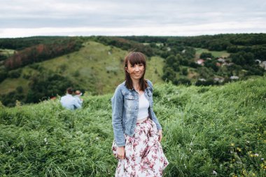 Denim ceket ve etek çiçek baskı çayır üzerinde yürüme ile güzel kadın