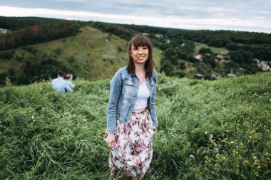 Denim ceket ve etek çiçek baskı çayır üzerinde yürüme ile güzel kadın