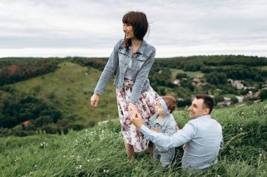 Anne kız ve çim üzerinde oturan babası ile elele