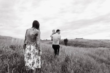 Siyah beyaz resim sahada bulutlu gökyüzü arka plan üzerinde yürüyen çocuk ile genç ailesinin