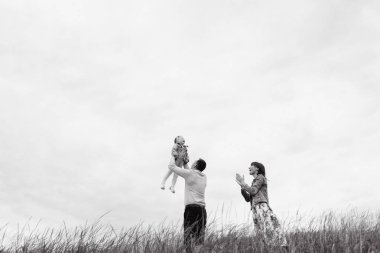 Oynamak ve eğlenmek çayır bulutlu gökyüzü arka plan üzerinde aile alttan görünüm