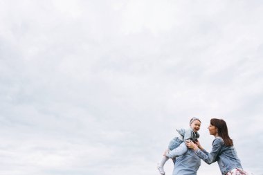 Oynamak ve eğlenmek çayır bulutlu gökyüzü arka plan üzerinde aile alttan görünüm