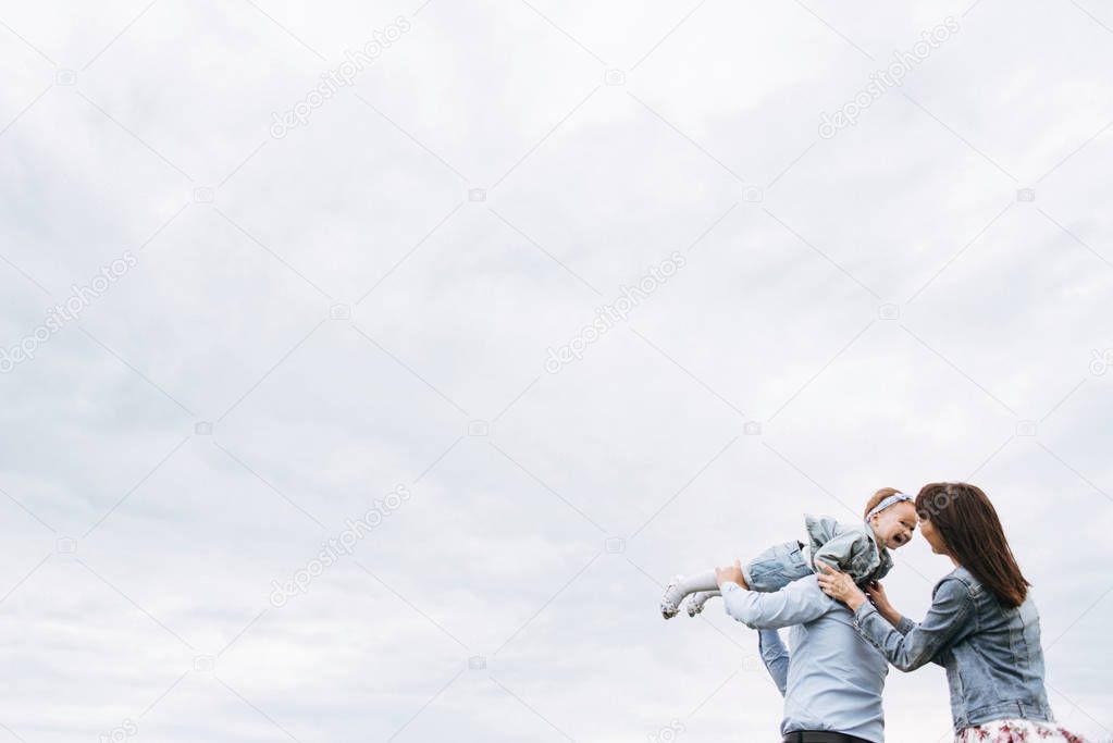 Bottom view of family playing and having fun on meadow against cloudy sky background