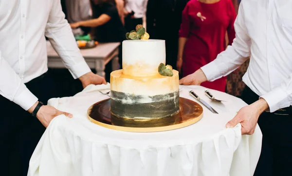 Waiters serving holiday table with wedding cake
