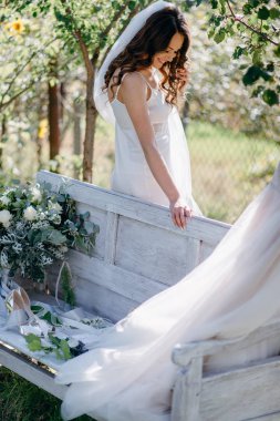 Gelin dalgalı saç ve gülümseyen ve tezgah bahçesinde ayakta peçe ile yan görünüm