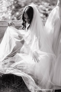 Bankta oturan ve peçe ile kapsayan mutlu gelin