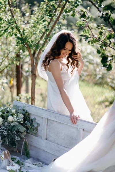 ウェーブのかかった髪と庭のベンチでベール立っている花嫁の肖像画 — ストック写真