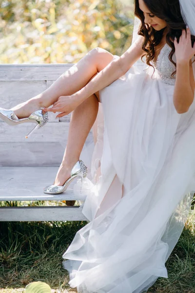 ベンチに座って 銀のハイヒール履きの花嫁 — ストック写真