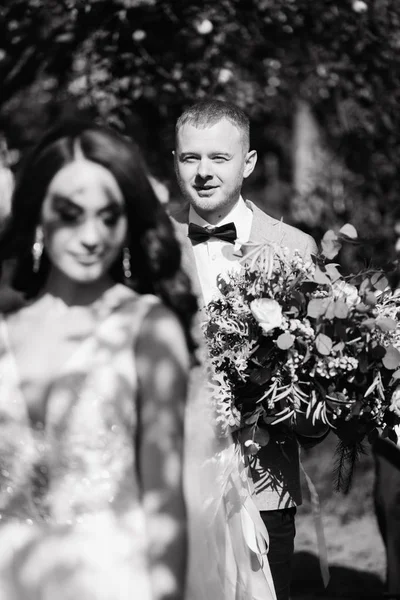 Glückliche Braut Spaziert Garten Und Bräutigam Mit Hochzeitsstrauß Hinterher — Stockfoto