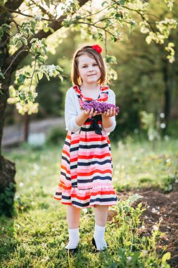 Leylak dalı tutarak ve çiçek açan elma bahçesinde kamera poz sevimli kız