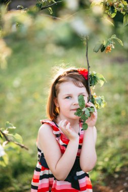 Çok dokunaklı ve çiçek açan elma şubesine poz çizgili elbiseli kız closeup